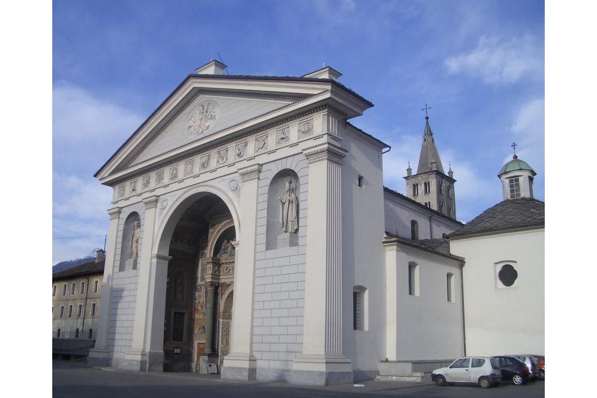 Facciata storica della Cattedrale di Aosta con dettagli architettonici e montagne sullo sfondo.