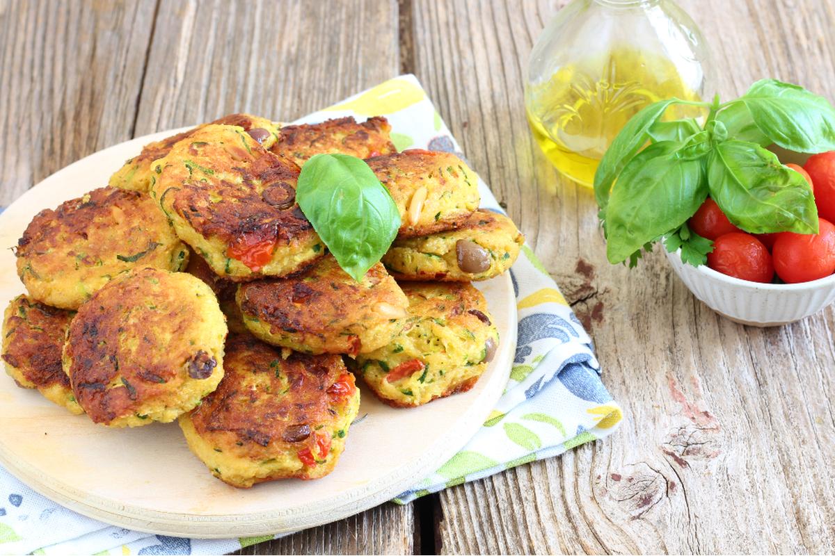 Polpette di zucchine dorate, croccanti e profumate, servite su un piatto rustico siciliano.